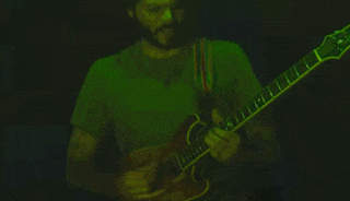 a man in a green shirt playing a guitar