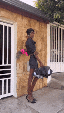 a woman is standing in front of a stone building holding a purse