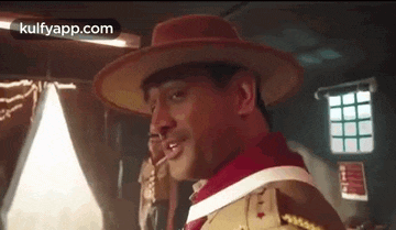 a man in a hat is standing in a room .