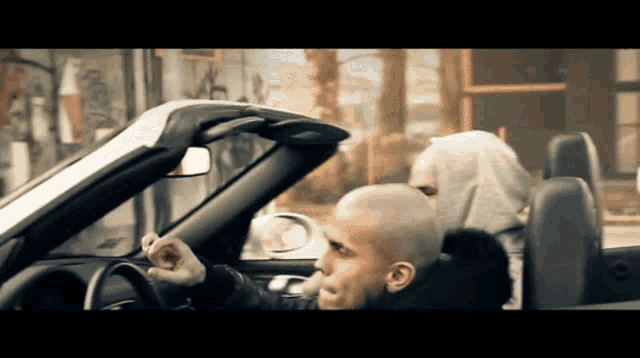 a man with a shaved head is sitting in a car