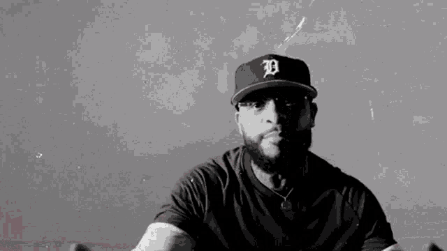 a black and white photo of a man wearing a baseball cap with the letter d on it .