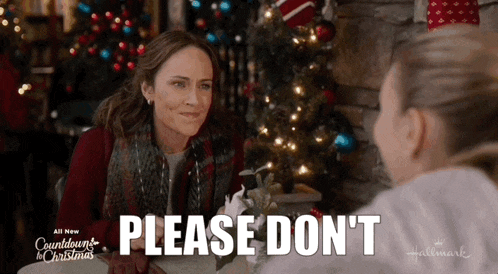 two women are sitting at a table with a christmas tree in the background and one of them is saying please don 't
