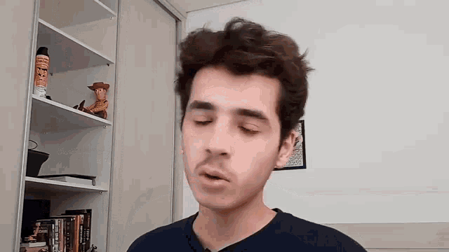 a young man with a mustache is standing in front of a shelf with a toy story woody on it .