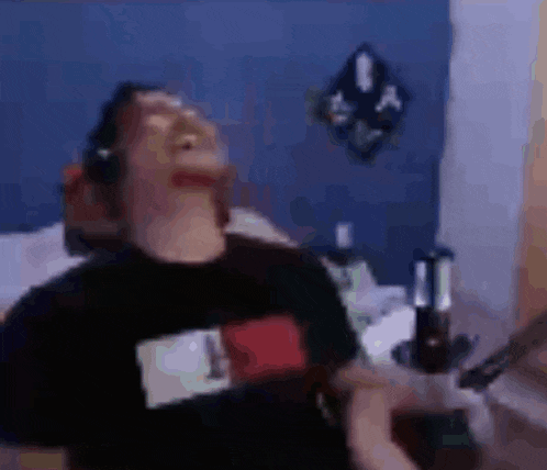 a man wearing headphones is sitting on a bed with a bottle of beer in his hand .