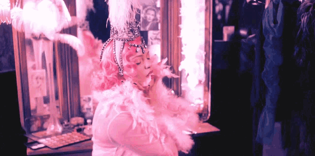 a woman with pink hair and feathers on her head