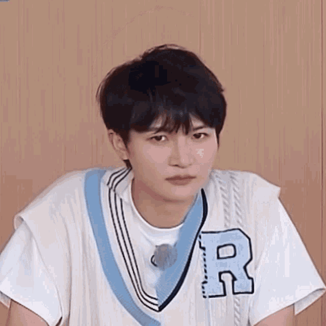 a young man wearing a white shirt and a blue vest with the letter r on it