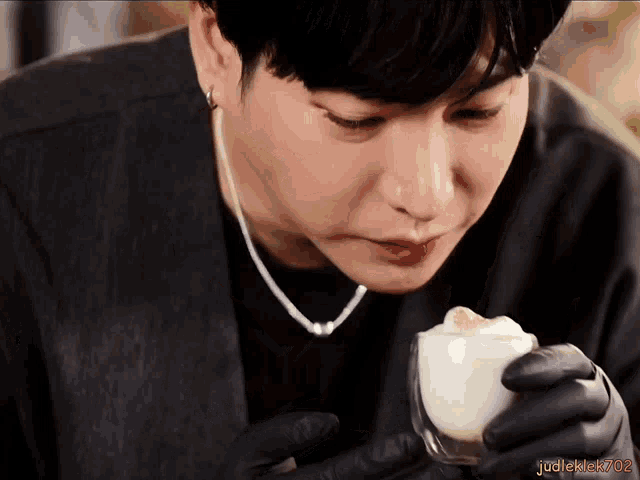 a man in black gloves smells a cup of coffee with the watermark judleklek702 on the bottom