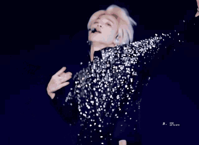 a man wearing a sequined shirt with a microphone in his ear