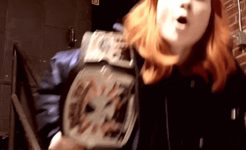 a woman with red hair is wearing a wrestling championship belt