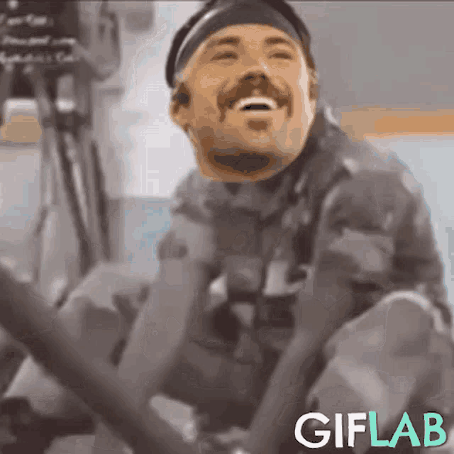 a man in a military uniform is sitting down and laughing with the words giflab below him