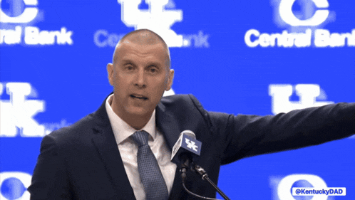 a man in a suit and tie is speaking into a microphone in front of a blue background that says central bank on it