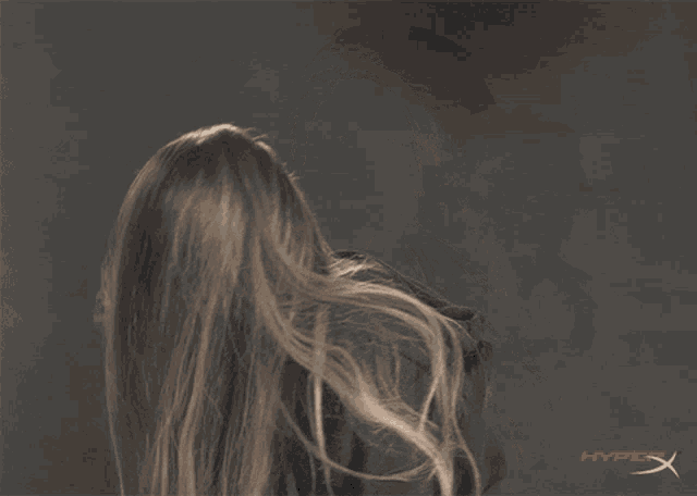 a woman 's hair is blowing in the wind and the hyperx logo is visible