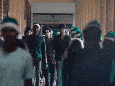 a group of people wearing santa hats are walking down a long hallway