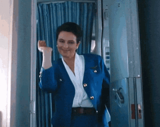 a woman in a blue suit is standing in a doorway with her fist in the air
