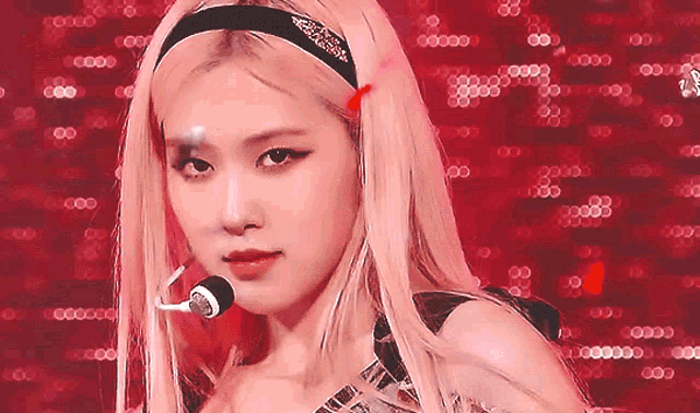 a close up of a woman wearing a headband and a microphone on a red background .