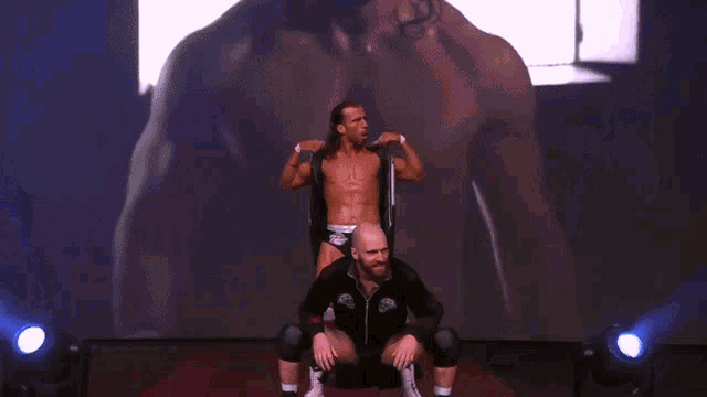 a wrestler is sitting on the back of another wrestler with the word ro on the back