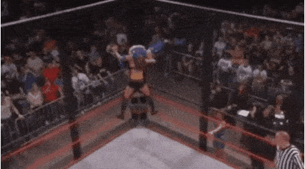 a woman is jumping in the air in a wrestling ring while a referee looks on .