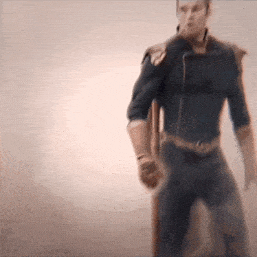 a blurry picture of a man in a superhero costume standing in front of a white wall .