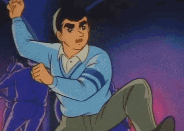 a man in a blue sweater is standing in front of a purple background with his fist in the air