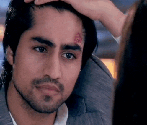 a close up of a man 's face with a woman 's hand on his forehead .