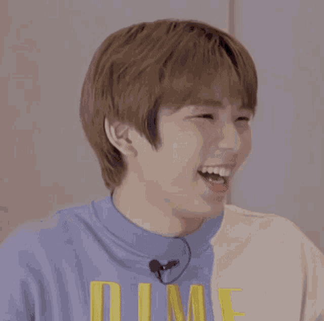 a young man wearing a blue shirt with the word dime on it is laughing