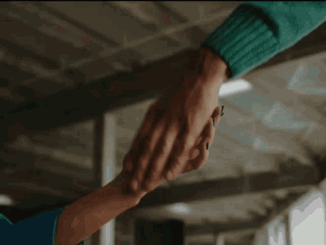 a person holding another person 's hand with a green sweater on