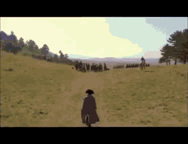a blurry picture of a man walking in a field with horses in the background