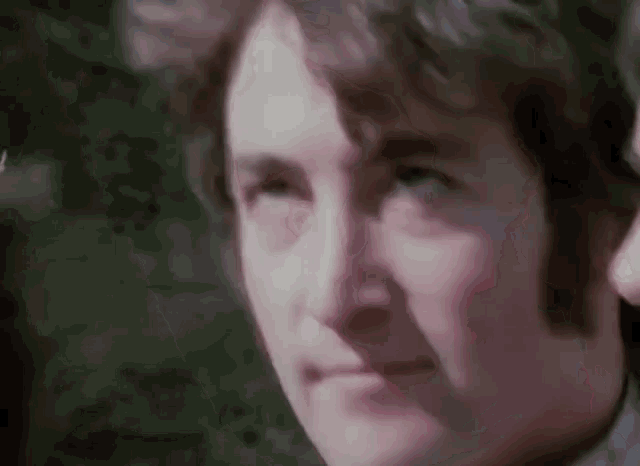 a close up of a man 's face with a blurred background looking at the camera .