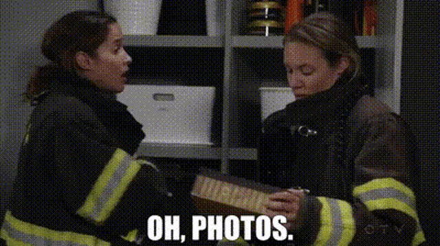 two firefighters are standing next to each other and one of them is holding a piece of paper that says " oh photos "