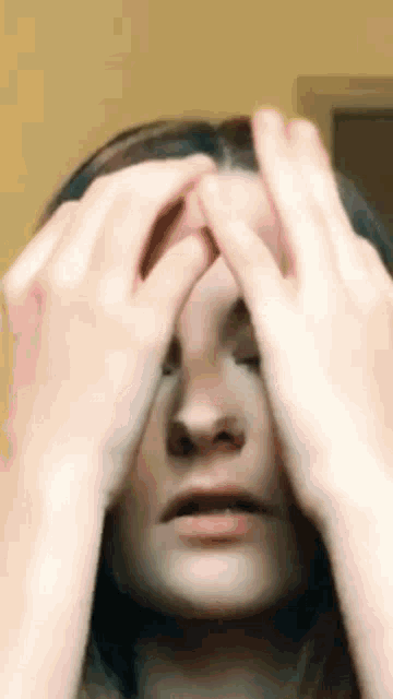 a woman with her eyes closed is holding her head with her hands