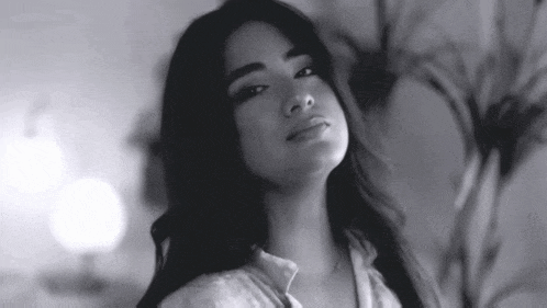 a black and white photo of a woman with long hair looking at the camera