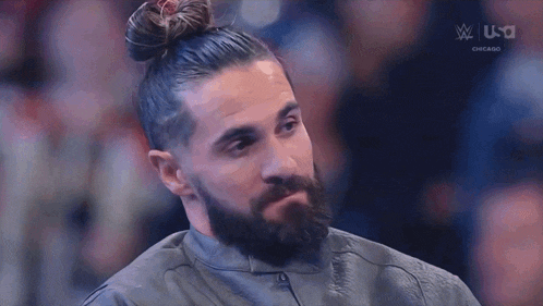 a man with a beard and a bun on his head is sitting in a chair .