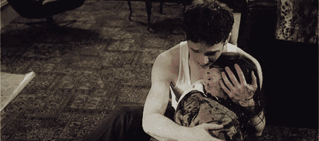 a man in a white tank top is holding a woman with blood on her hands