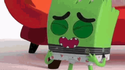 a green cartoon character is standing in front of a red couch with his eyes closed .