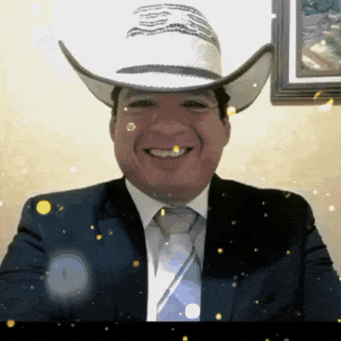 a man in a suit and tie is wearing a cowboy hat and smiling