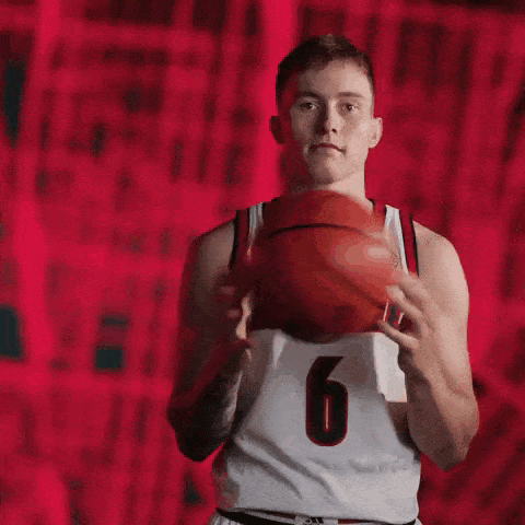 a young man in a louisville jersey is holding a basketball in his hands .