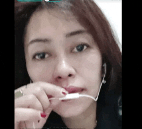 a woman wearing headphones is holding a charger in her mouth .
