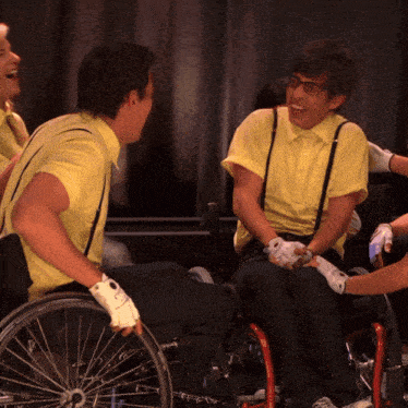 a man in a yellow shirt and suspenders is sitting in a wheelchair