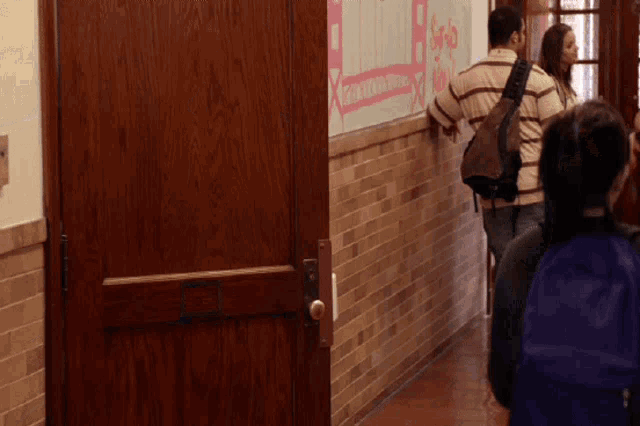 a group of people walking down a hallway with a sign on the wall that says ' i love you ' on it