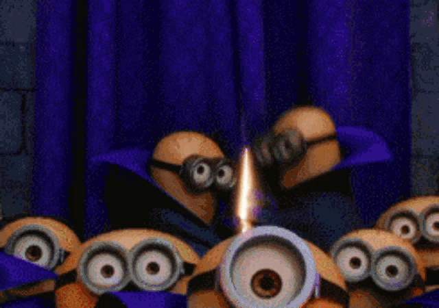a group of minions are standing in front of a purple curtain with a flame coming out of one of their eyes .