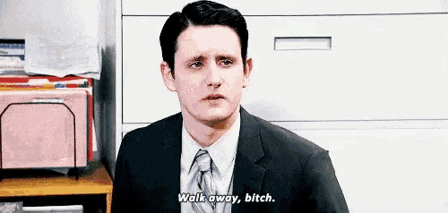 a man in a suit and tie is standing in front of a filing cabinet and saying `` walk away , bitch . ''