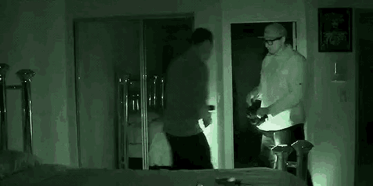 two men are standing next to each other in a dark room .