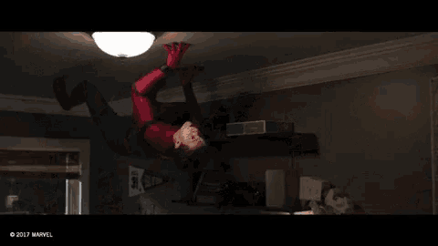 a man in a spiderman costume is hanging upside down