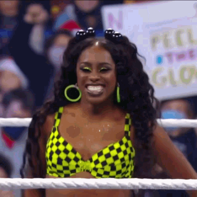 a woman in a yellow and black checkered bikini is smiling in a ring .