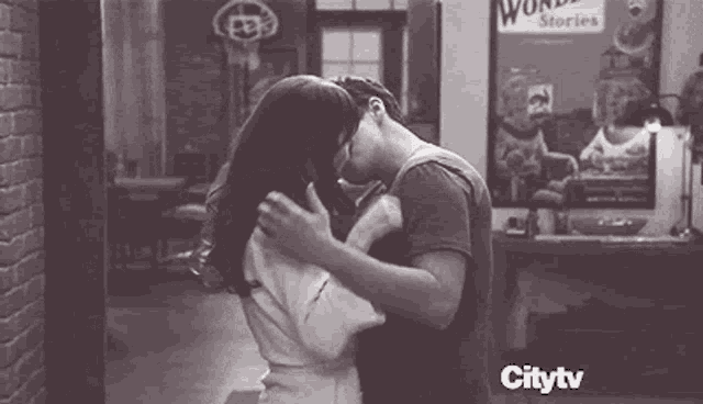 a man and a woman are kissing in front of a sign that says wonder .