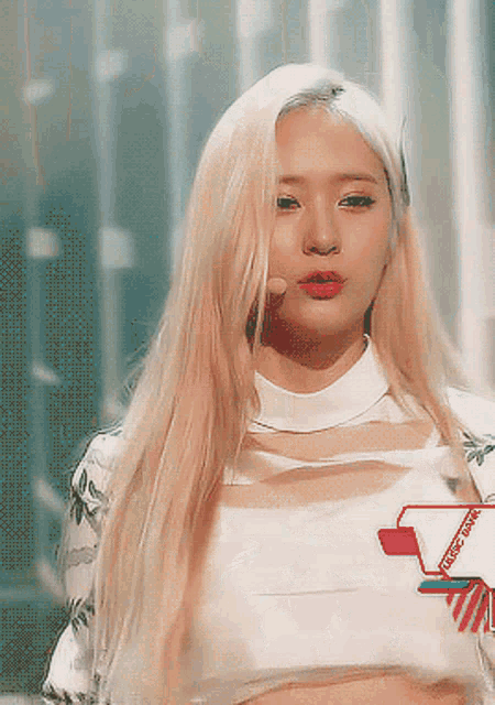 a woman with long blonde hair is wearing a white crop top with a sticker on it that says ' kpop ' on it