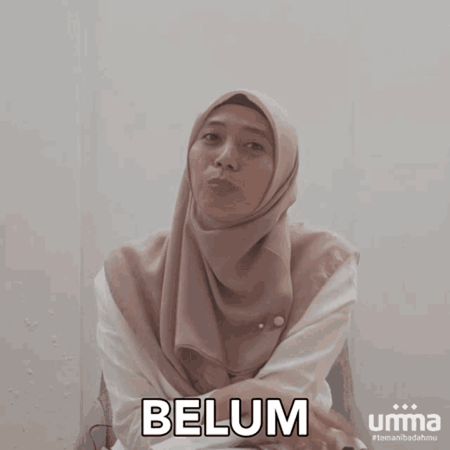 a woman wearing a hijab is making a funny face and the word belum is above her head