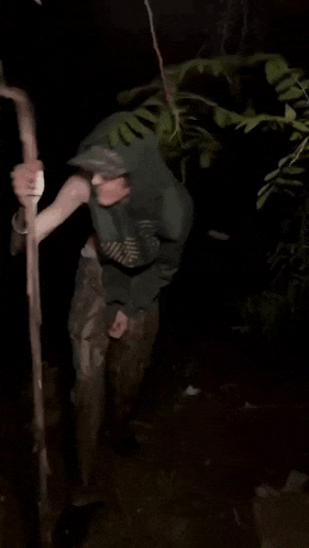 a man in a hoodie is holding a stick and wearing a flashlight