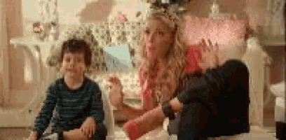a woman is sitting on the floor talking to two children .