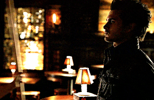 a man is standing in a dark room with a lamp in front of him